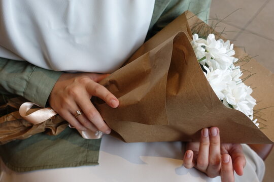 hand of young girl holding a bouquet of white daisies