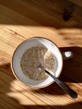 A while bowl with oat and milk rested on a wooden table