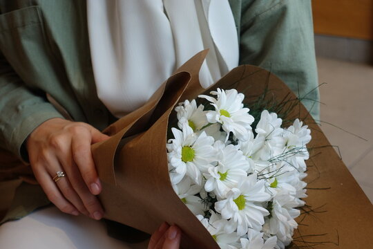 Young girl holding a bouquet of white daisies wearing hijab