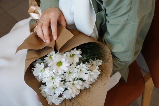 Young girl holding a bouquet of white daisies wearing hijab