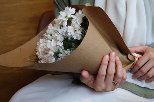 Young girl holding a bouquet of white daisies wearing hijab