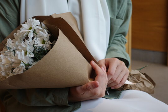 Young girl holding a bouquet of white daisies wearing hijab