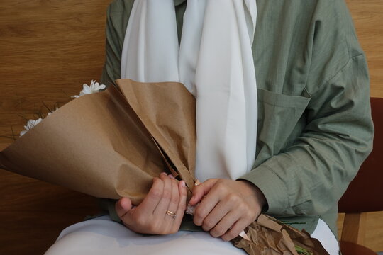 Young girl holding a bouquet of white daisies wearing hijab
