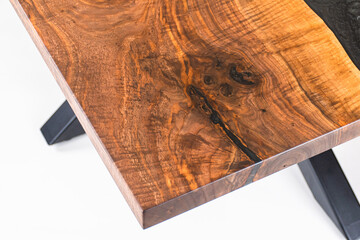Close up of a Curly Bastogne Walnut wooden dining table with black epoxy resin and metal legs....