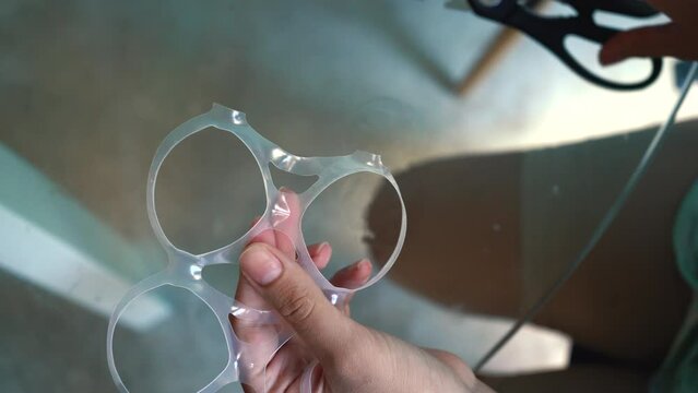 Plastic rings for packaging beer female hands are removed from the iron can. Cutting plastic with scissors in an environmentally friendly way. High quality 4k footage