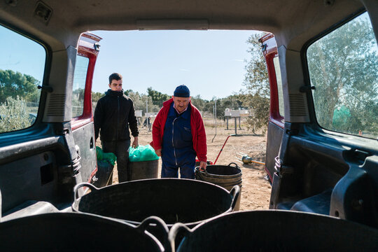 Male gardeners putting baskets in car trunk