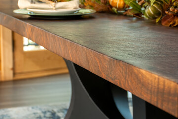 Close up of walnut solid wooden dining table with black metal base legs and fall decorations. Table...