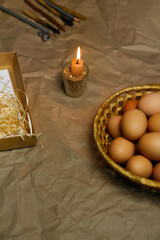 Candle with light. Rustic background. Tools for decorating Paschal eggs, Pysankas. Collection of eggs. Homemade pen for drawing eggs. Preparation for holiday. Craft paper. Tradition. Vertical