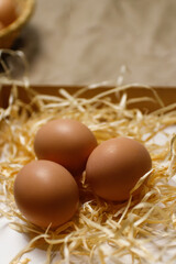 Closeup rustic eggs on hay background. Easter craft box with brown eggs on eco background. Chicken eggs on craft table with hay and straw. Close-up view of raw product. Wooden straw