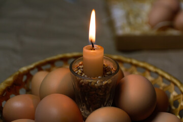 Candle with light. Rustic background. Paschal eggs, Pysankas. Collection of eggs on background.  Preparation for holiday. Craft paper. Tradition. Orthodox. Brown egg