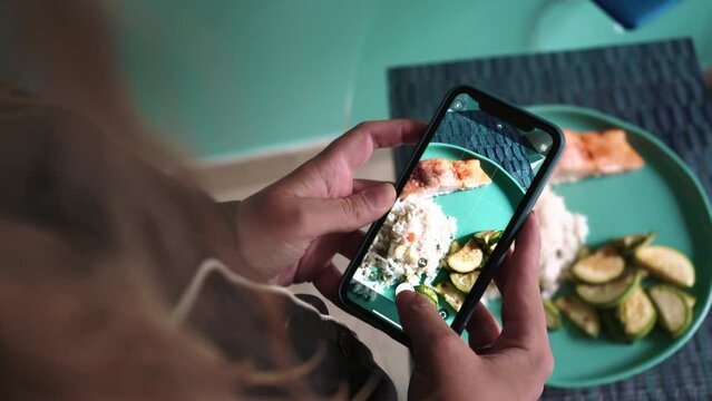  woman sits at home in pajama and photographs her lunch on a smartphone. close up shot. Rice and salmon with vegetable marrow . High quality 4k footage