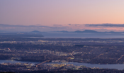 Vancouver Cityscape, British Columbia, Canada on the West Coast of Pacific Ocean. Aerial Panoramic View at Sunset Twilight. Modern City lights. Taken from Grouse Mountain.