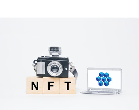 A miniature camera, laptop with blockchain, Ethereum symbol and NFT word. A non-fungible token (NFT) is a non-interchangeable unit of data stored on a blockchain. Can sold and traded
