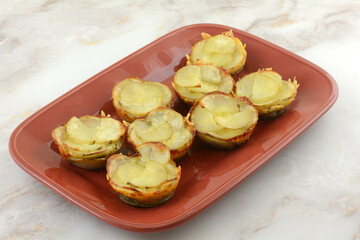 Baked potato and shredded mozzarella cheese cups on red red serving plate
