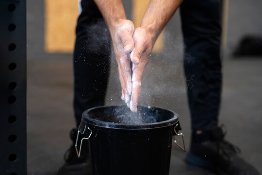 Crop sportsman applying chalk on hand before training