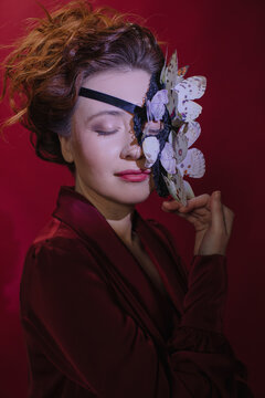 Dreamy portrait of red head woman in butterflies mask 