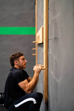 Young sportsman hanging on peg board