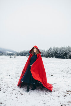 Young woman wearing red cloak in snow