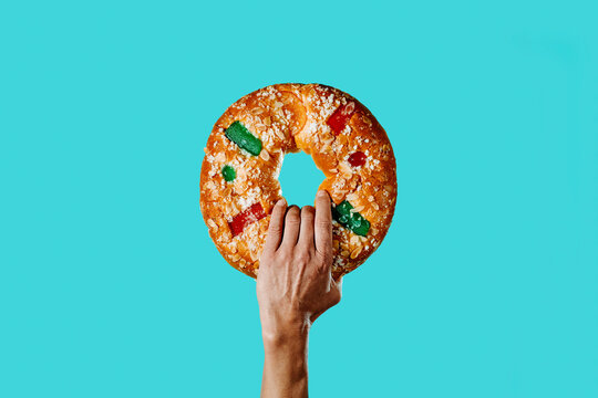 man holds a spanish king cake in his hand