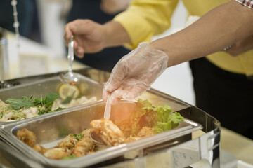 closeup hand wearing gloves scooping food, catering, dinner time, prevent Coronavirus disease (covid 19)