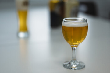 A glass filled with beer stands on a white table