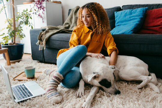 Girl streaming on computer petting her dog at home