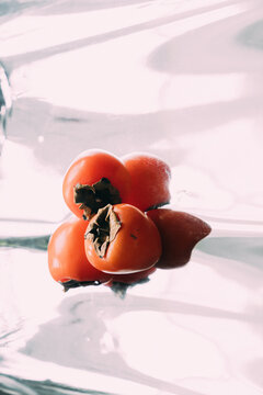 Fruits on a mirror surface, persimmon.