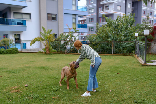 a woman plays with dog in the yard of her house