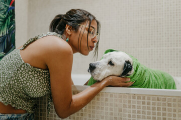 Dog wrapped in towel on a bathtub