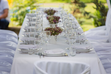A festive table setting with beautiful bouquets of field wild flowers outdoors. Celebrating of Birthday or wedding outdoor. Party. Catering