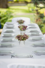 A festive table setting with beautiful bouquets of field wild flowers outdoors. Celebrating of Birthday or wedding outdoor. Party. Catering