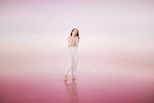 Read head woman in white dress on the pink background 