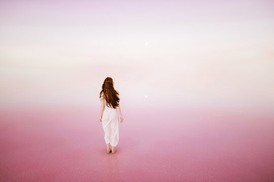 Back view of a woman standing in a pink water 