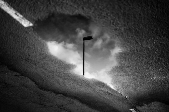 A lamppost reflected in a puddle.