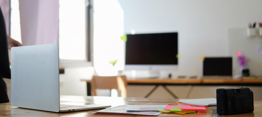 Computer laptop, sticky notes and colour swatches on white table at creative office.