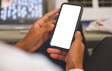 Over shoulder view of young man hands holding smart phone empty screen while sitting at workplace.