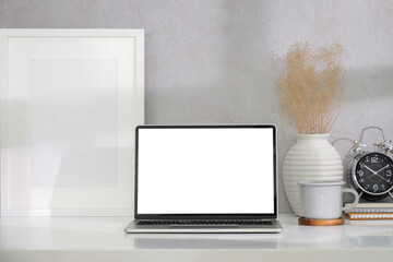 Front view mockup computer laptop with empty display ,coffee cup and picture frame on white table.