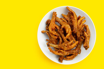 Fried chicken feet in white plate on yellow background.