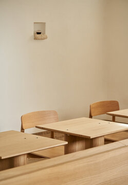 Timber tables and chairs against beige wall