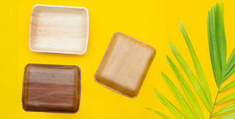 Betel palm leaf plates on yellow background.