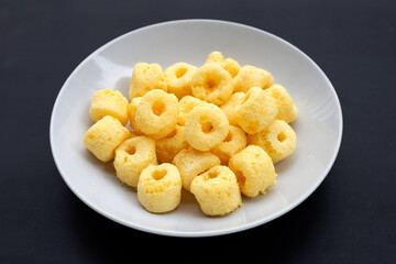 Roller corn snack in plate on dark background.