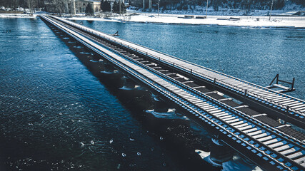 Fototapeta premium Old railroad tracks covered in over an icy river.