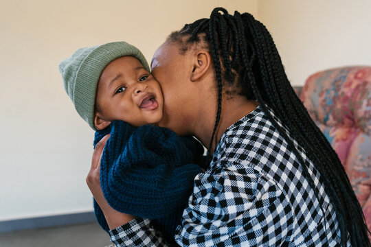 Black mother kissing cute toddler