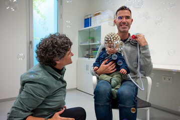 Medical personnel preparing crying child for EEG test