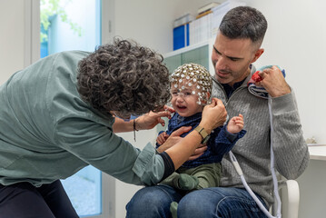 Medical personnel preparing crying child for EEG test