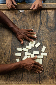 two unrecognizable hands shuffle the dominoes