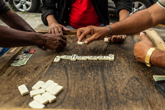 friends playing dominoes on a wooden table.