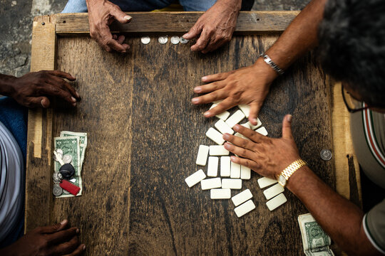 friends playing dominoes on a wooden table.