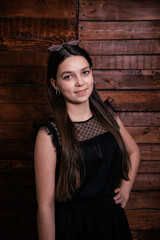 Fototapeta premium Cute portrait of a girl on a wooden background. Emotional child in a dress.