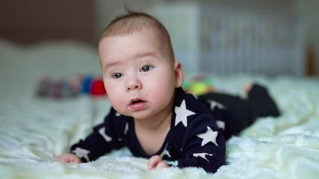 Small cute baby on the bed. Funny little child portrait smilling.